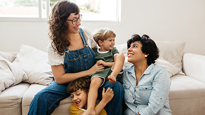 two parents sitting and playfully holding two children