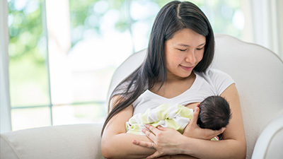 smiling parent nursing their infant 