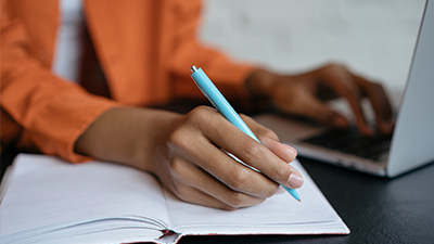 close up of person's arm writing with a light blue pen.