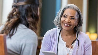 smiling doctor in focus talking with a patient in the foreground.