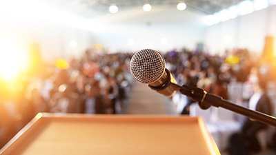 microphone in focus with a audience in the background.