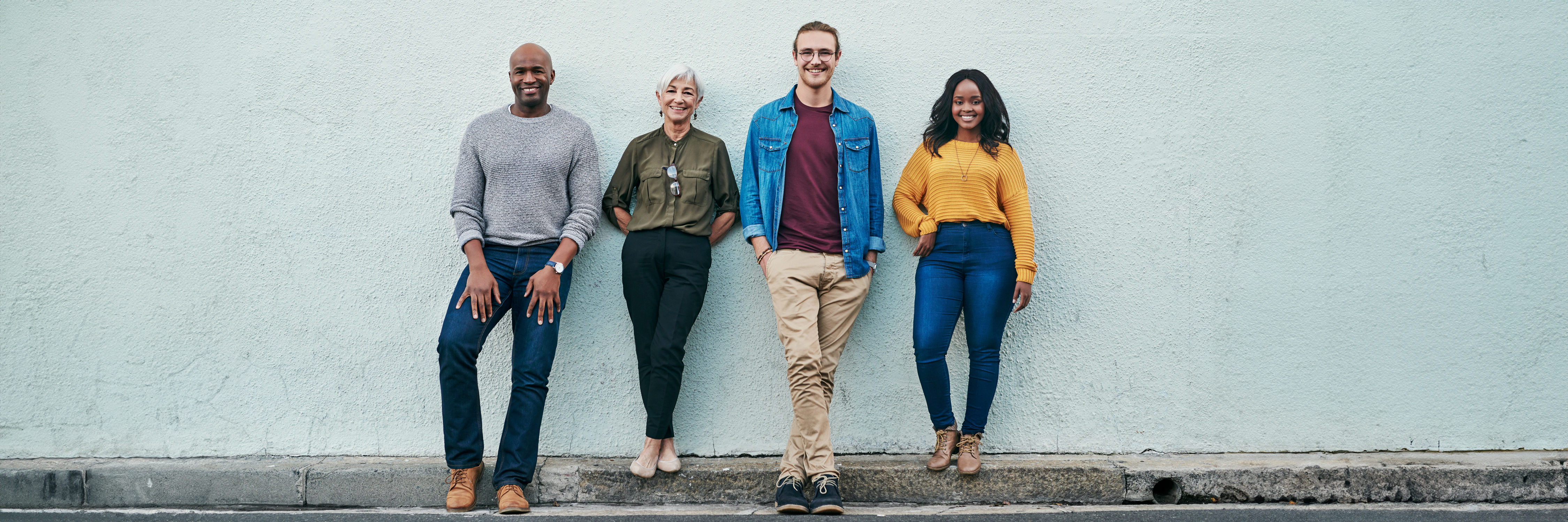 4 people standing against a wall