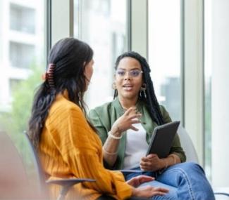 Two women seated in a lobby talking.