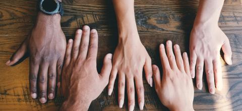five human hands on brown surface