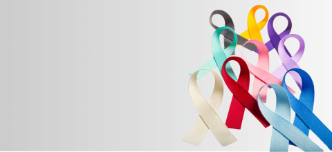Stock photo of different colored cancer awareness ribbons on a gray background.
